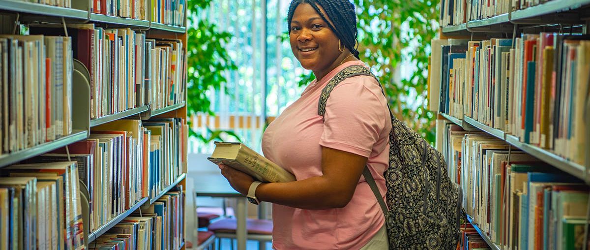 African American young woman beside library shelves