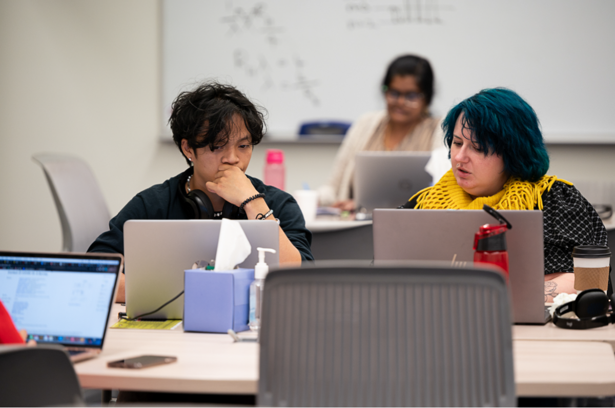 Tutor helping student on laptops in Tutoring Center
