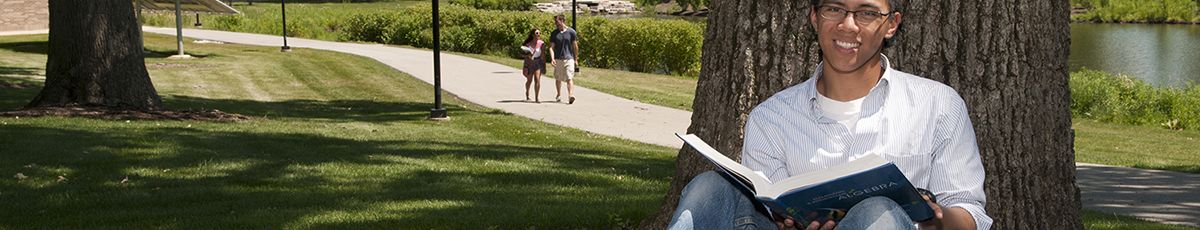 student reading book by tree
