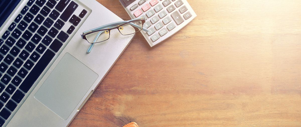 Stock office desk with laptop computer, notepad and calculator