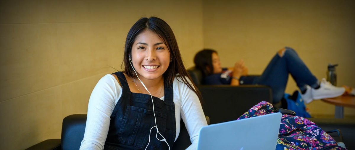 Student with a laptop computer smiling