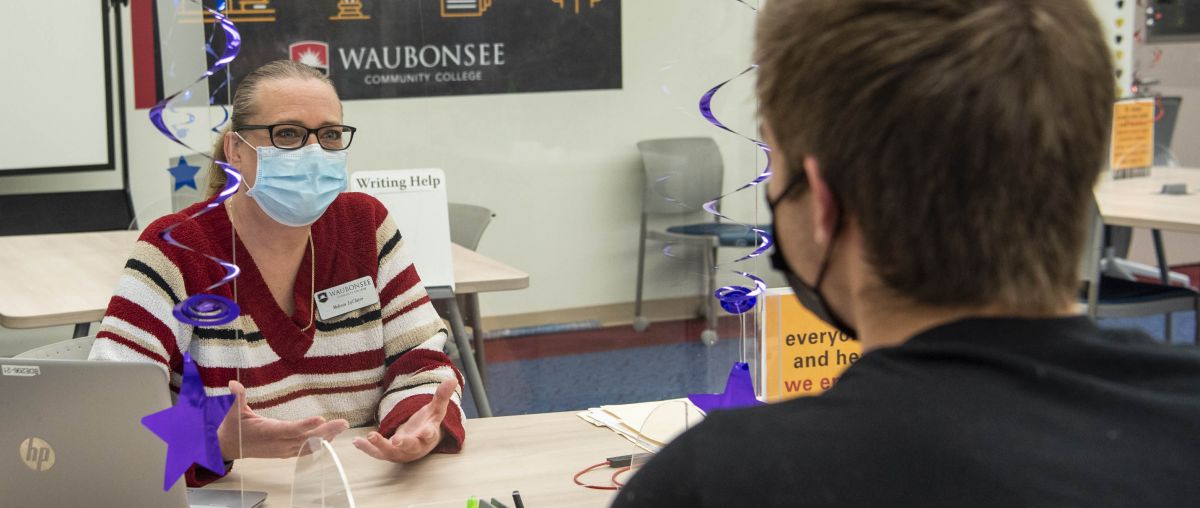 Masked tutor with student in Tutoring Center