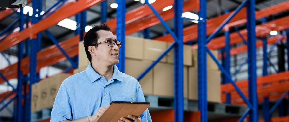 Worker with clipboard inspecting warehouse