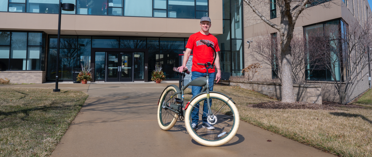 Dr. Brian Knetl on a bike in front of the Student Center