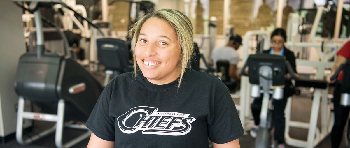 Female student with Chiefs shirt using fitness center