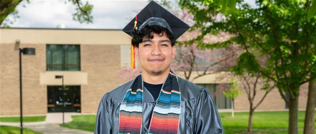 Jorge Lagunas Delgado, of Aurora Waubonsee graduate posing in cap and gown 