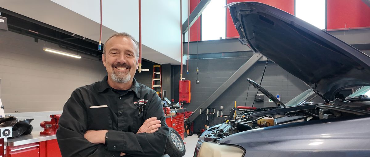 Rick Verhaagen standing in front of a car with hood open, in the Technical Education Center