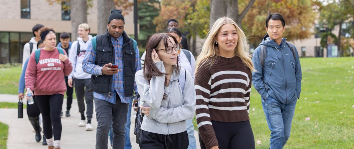 Several students walking outside on the campus pathways during fall