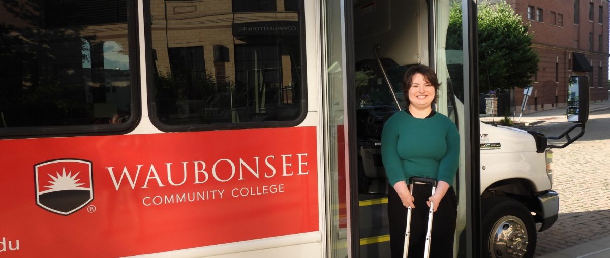 Krystal Donnelley posing in front of Waubonsee shuttle bus