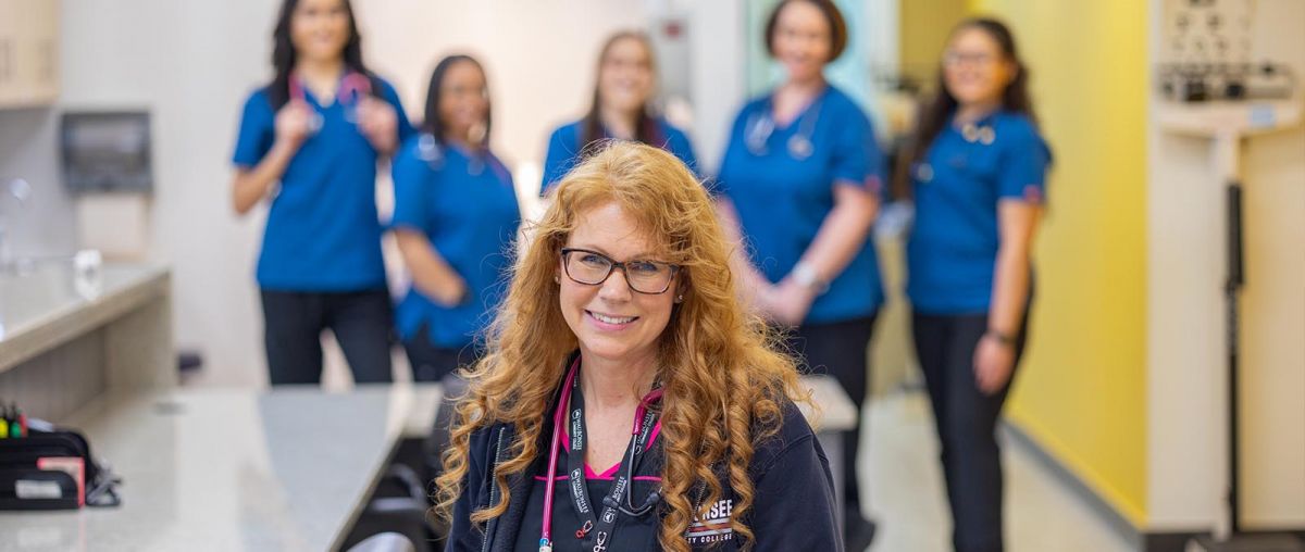 Lisa Giese, Assistant Professor of Medical Assistant and Phlebotomy standing in front of students