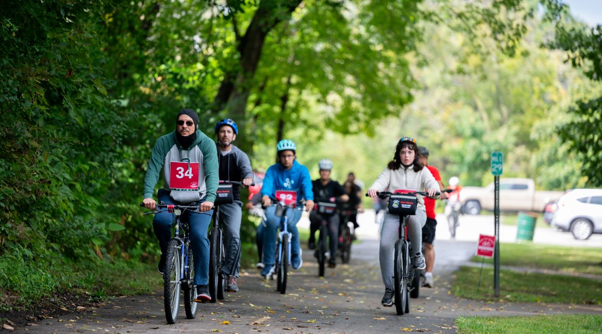 several bicyclists riding on a path going through trees