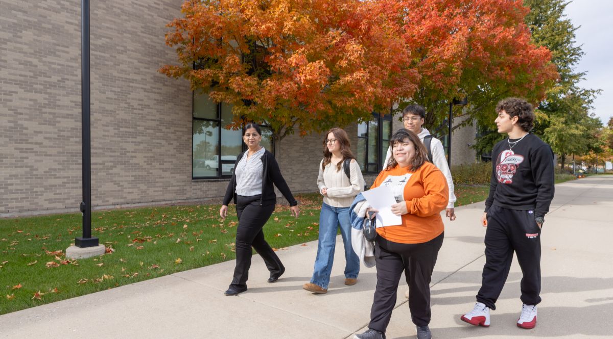 Group of students being led on a campus tour outside on path during fall