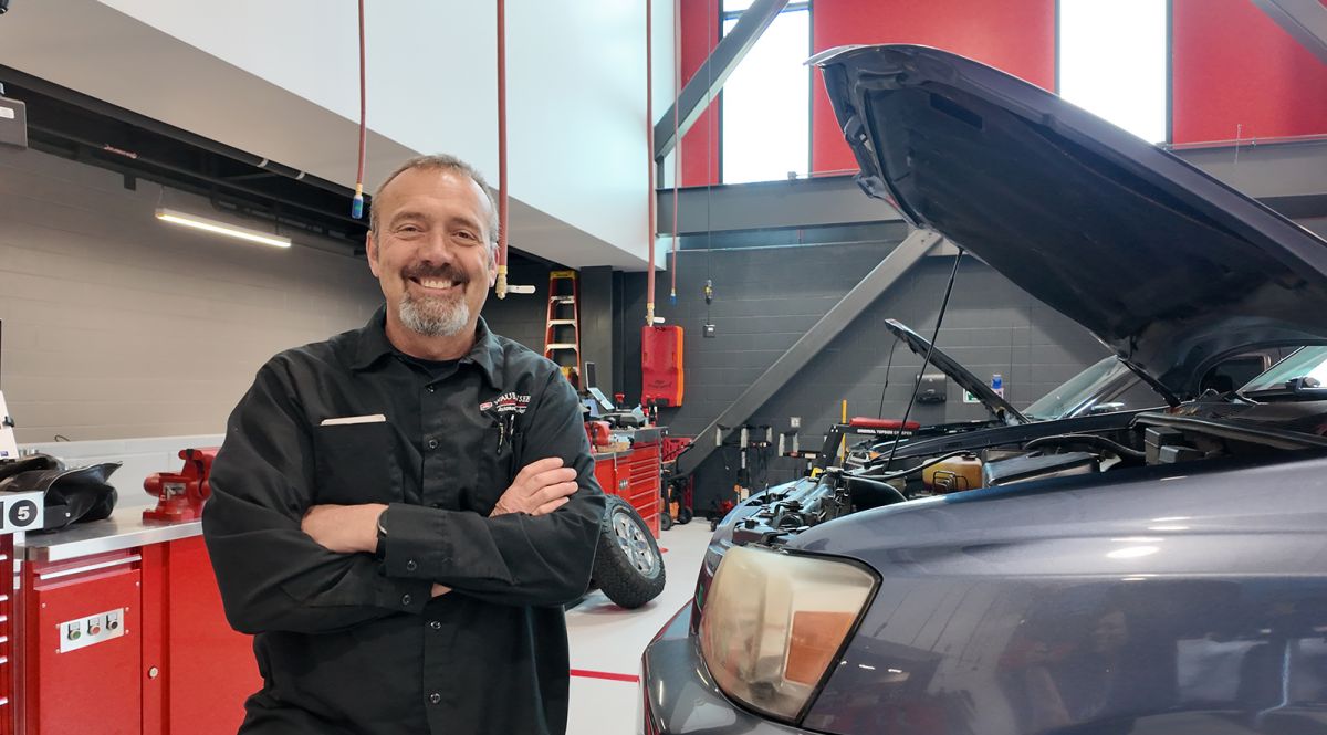 Rick Verhaagen standing in front of a car with hood open, in the Technical Education Center
