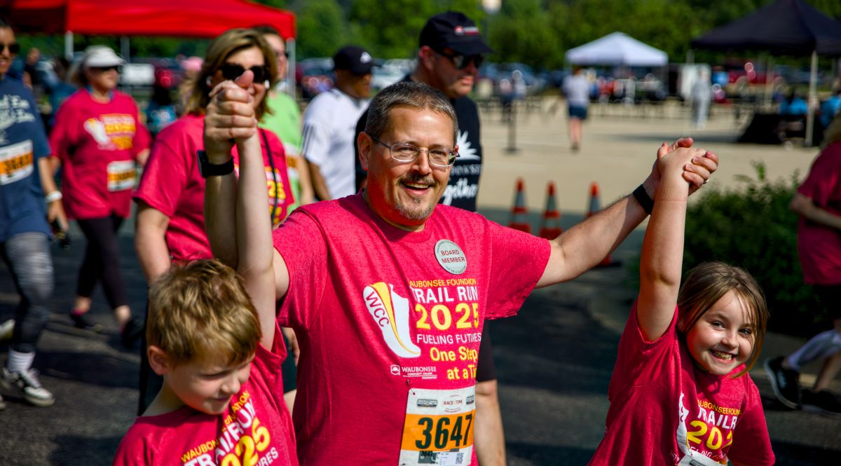 Dad holding his kids hands up at the 2025 trail run