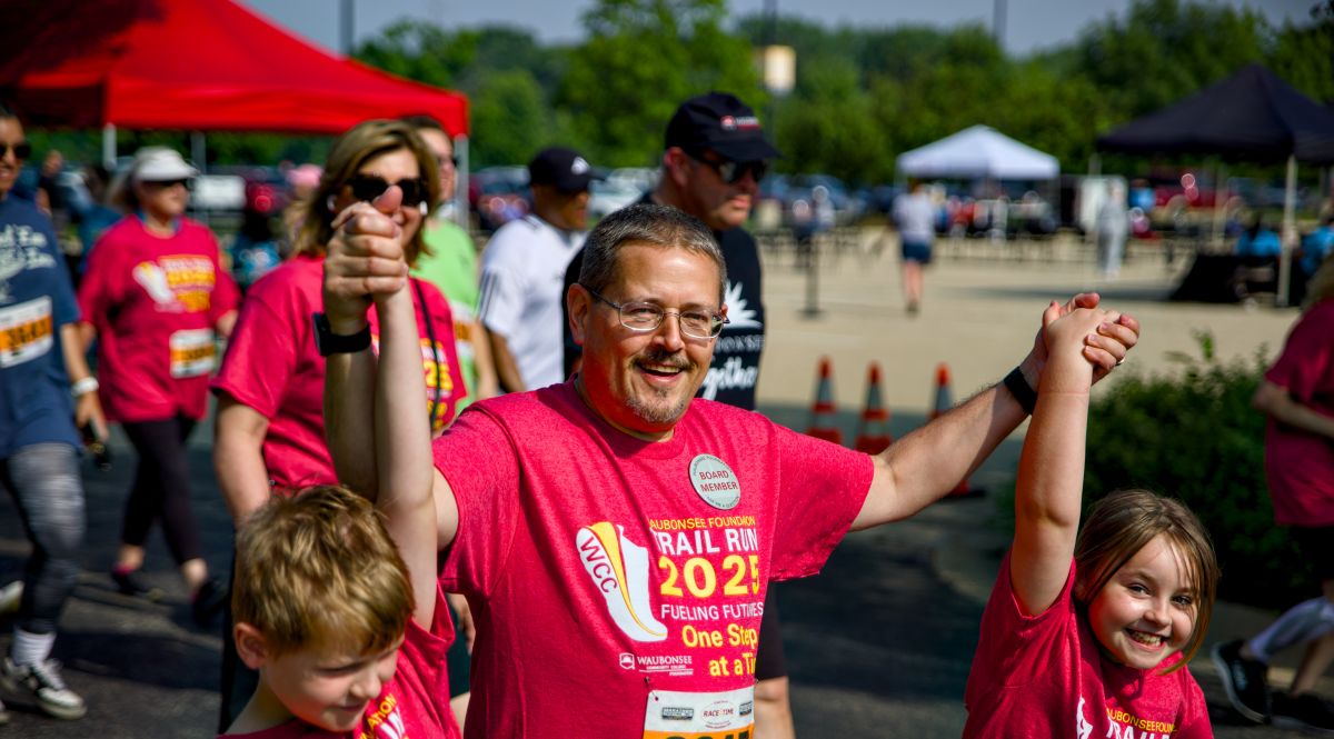 Dad holding his kids hands up at the 2025 trail run