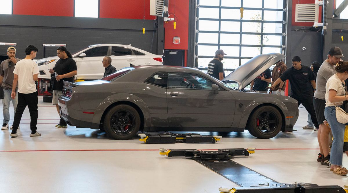 Automotive Technology students and guests near a dodge Challenger in the TEC building