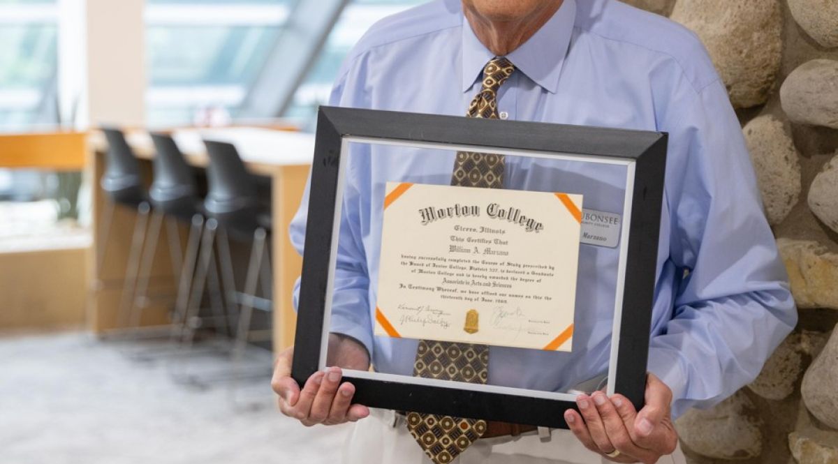 Dr. Bill Marzano, Interim Assistant Dean, stands with his Morton College diploma