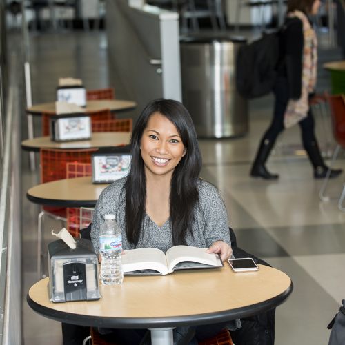 female student in cafeteria sitting and reading s