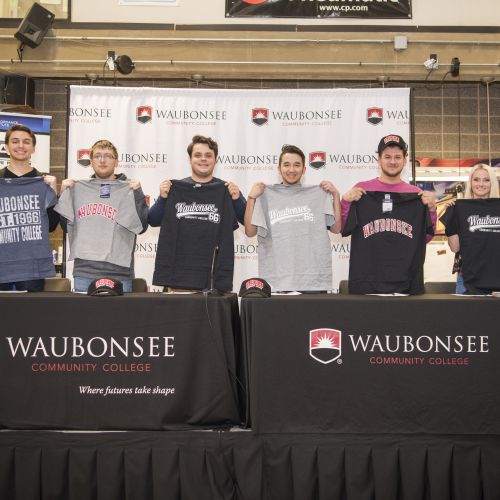 Photo of students signing commitments to Waubounsee Auto Tech Program