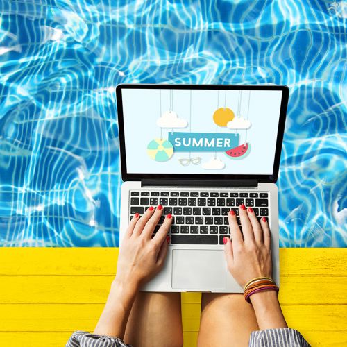 a student sits by the pool on a laptop
