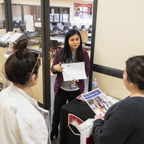 Staff member helping two visitors at Aurora Downtown Open House in 2019