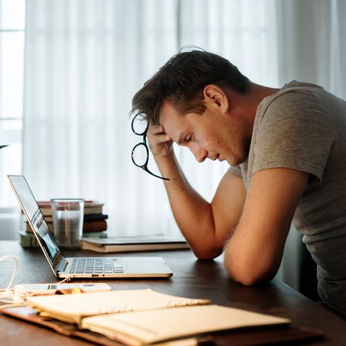 man looking stressed over papers