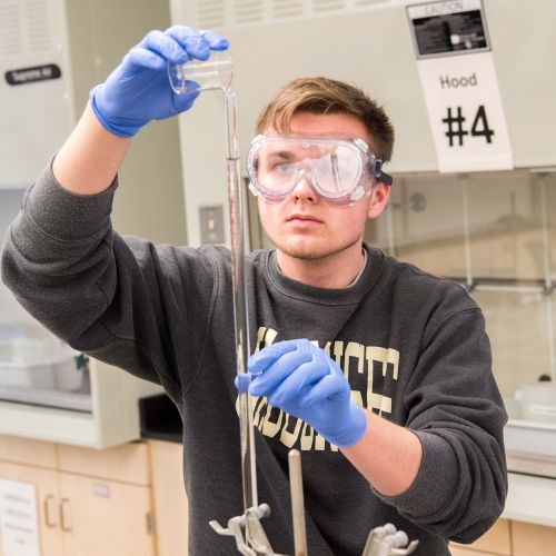 Student pouring chemicals into a beaker