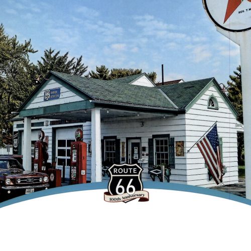 Classic car parked at gas station with Route 66 100th anniversary logo