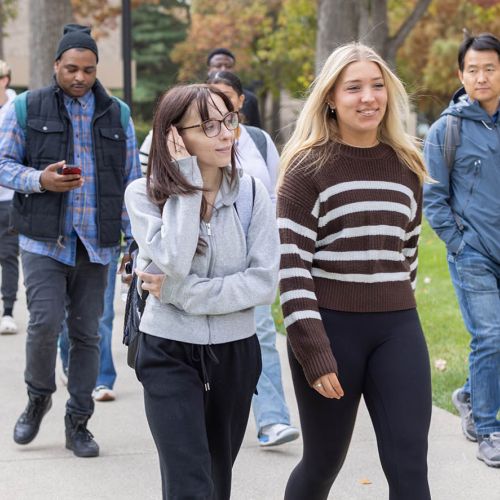 Several students walking outside on the campus pathways during fall