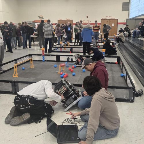 people walking around robot tournament and working on tournament