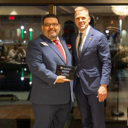 Hugo Saltijeral receives the Distinguished Alumni Award from Waubonsee Community College President Dr. Brian Knetl posing with award