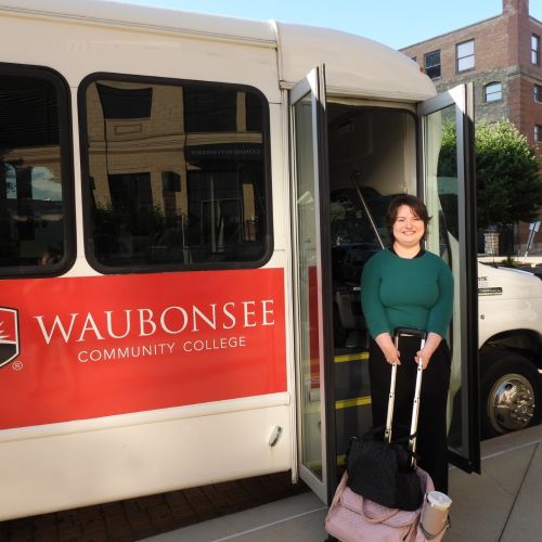 Krystal Donnelley posing in front of Waubonsee shuttle bus