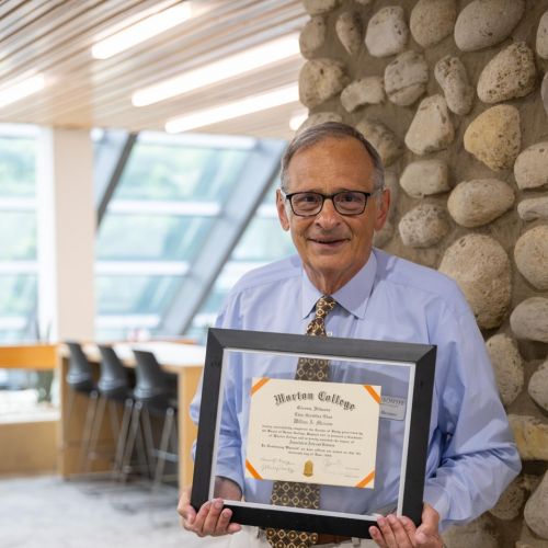 Dr. Bill Marzano, Interim Assistant Dean, stands with his Morton College diploma