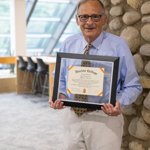Dr. Bill Marzano, Interim Assistant Dean, stands with his Morton College diploma