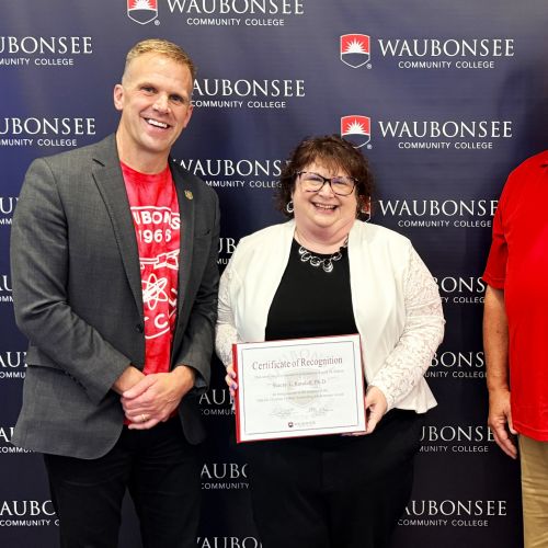 Waubonsee President Dr. Brian Knetl and Board of Trustee Patrick Kelsey present the 2026 Dr. Christine J. Sobek Outstanding Administrator Award to Dr. Stacey Randall, Executive Director of Institutional Effectiveness, Innovation, and Planning, at the August board of trustees meeting. 