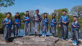 Graduates standing in front of lake huntoon