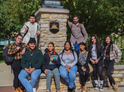 Group of students in front of pillar outside in fall