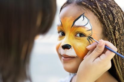 Child getting face painted to look like a tiger