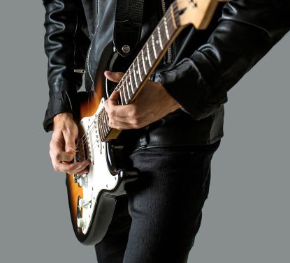 Musician wearing all black, playing guitar