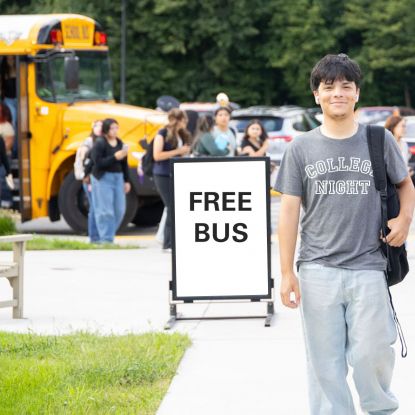 Student standing in front of a "Free Bus" sign