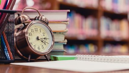 A clock next to a stack of library books