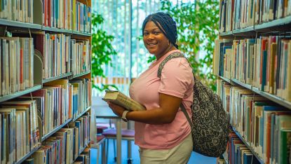 African American young woman beside library shelves