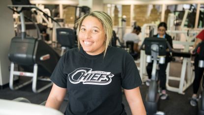 Female student with Chiefs shirt using fitness center
