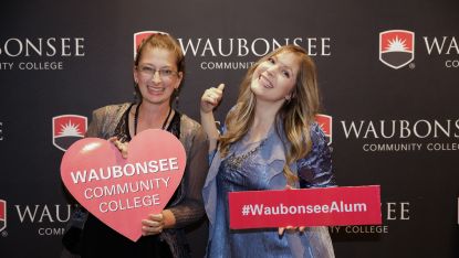 Two Waubonsee alum posing in front of a WCC background