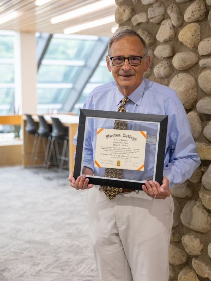 Dr. Bill Marzano, Interim Assistant Dean, stands with his Morton College diploma