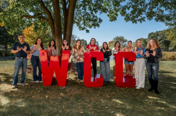 students waving the W standing around the giant WCC letters outside