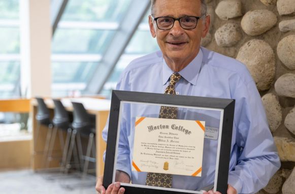 Dr. Bill Marzano, Interim Assistant Dean, stands with his Morton College diploma
