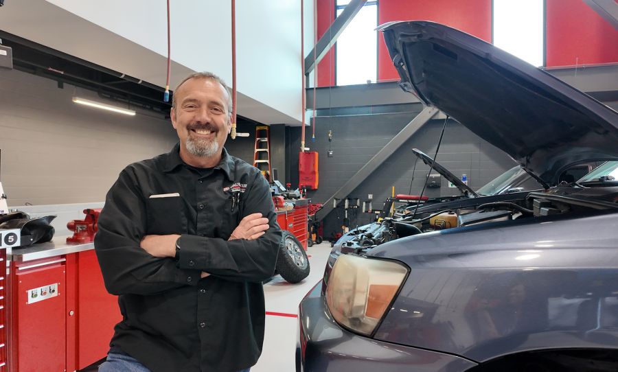 Rick Verhaagen standing in front of a car with hood open, in the Technical Education Center
