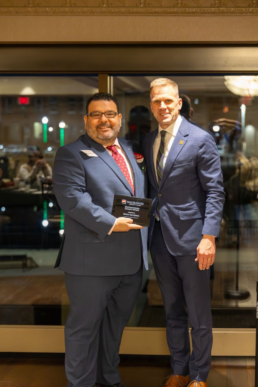 Hugo Saltijeral receives the Distinguished Alumni Award from Waubonsee Community College President Dr. Brian Knetl posing with award