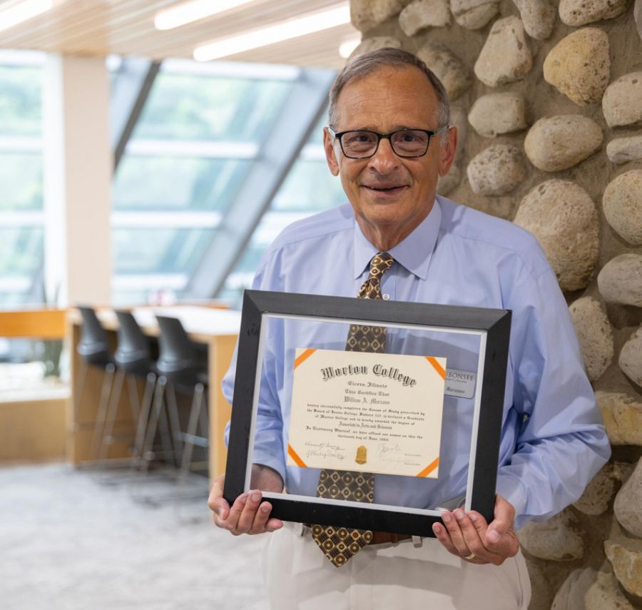 Dr. Bill Marzano, Interim Assistant Dean, stands with his Morton College diploma